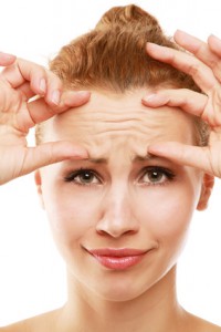 A young woman checking wrinkles on her forehead, closeup